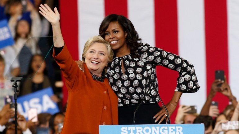La candidata a la presidencia de EEUU por el partido Dem&oacute;crata Hillary Clinton (i) saluda a sus seguidores junto a la primera dama. Michelle Obama (d).