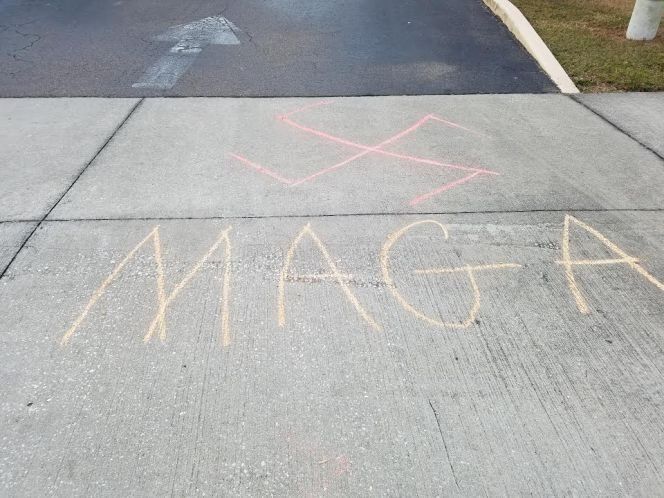 Grafitti pintado con tiza en el cemento, en una calle de St Petersburg, Florida. Se puede ver la cruz gamada (símbolo nazi) y las siglas MACA (make America great again, eslogan de campaña de Trump) 