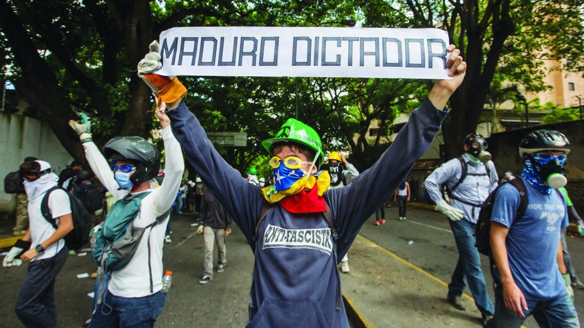 Un protestante alza un letrero en contra del dictador.