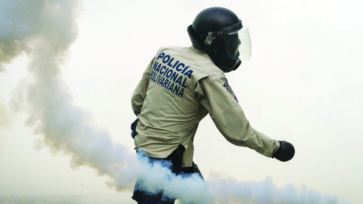 Un miembro de la Policía Nacional Bolivariana lanza bombas lacrimógenas. 