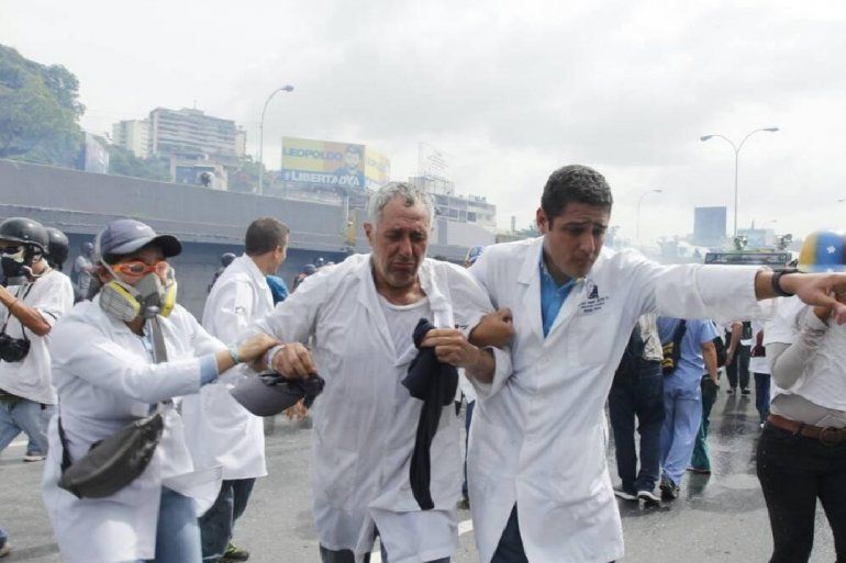 El diputado José Francisco Olivares ayuda a un colega médico afectado por las bombas lacrimógenas en la autopista Francisco Fajardo. 