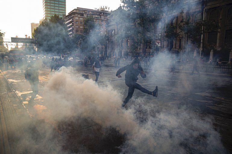 Un manifestante patea una lata de gas lacrim&oacute;geno arrojada por la polic&iacute;a cerca de la estaci&oacute;n Santa Luc&iacute;a del tren subterr&aacute;neo durante una protesta contra el creciente costo de las tarifas del metro y los autobuses, en Santiago, Chile, el viernes 18 de octubre de 2019. 
