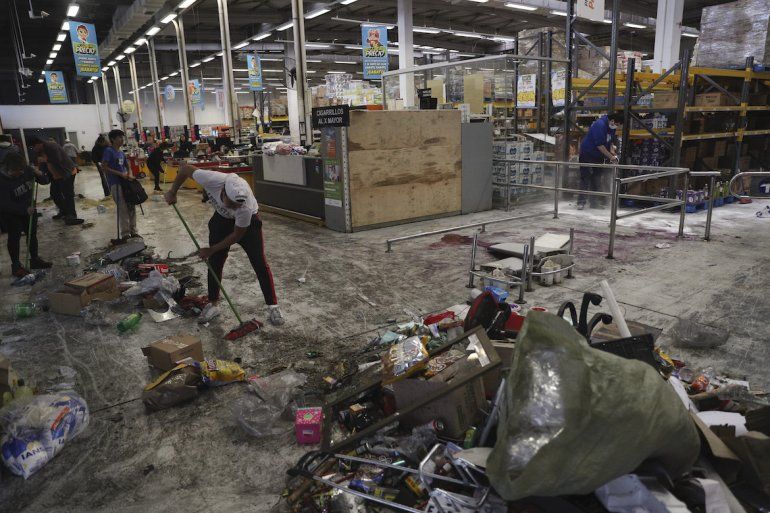 Trabajadores limpian un supermercado saqueado en Santiago de Chile el domingo 20 de octubre de 2019.