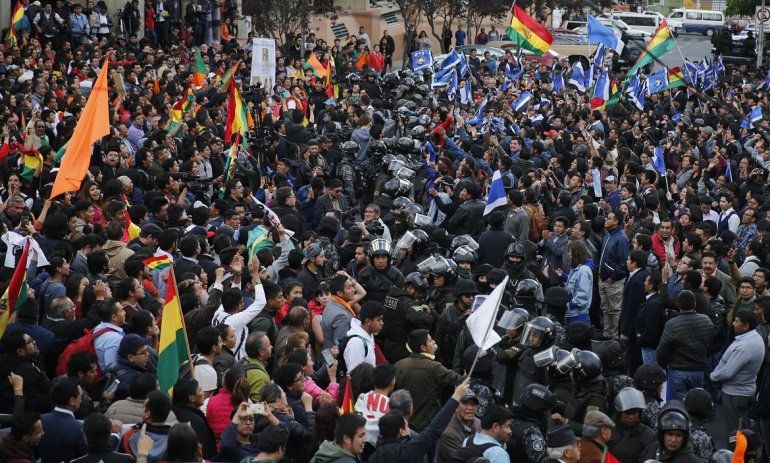 Una línea de policías separa a los simpatizantes del expresidente y candidato Carlos Mesa, izquierda, de los partidarios del presidente boliviano Evo Morales, que se postuló a su cuarto período, a las afueras del Tribunal Supremo Electoral en La Paz, Bolivia, el lunes 21 de octubre de 2019. 