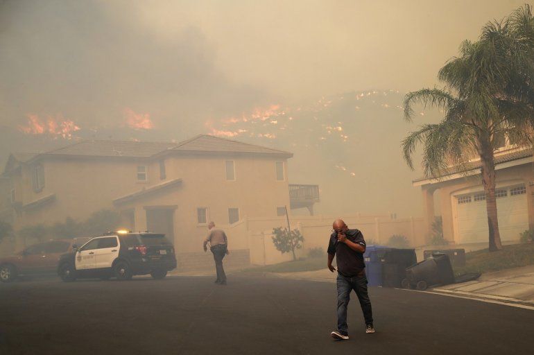 Un residente se cubre el rostro mientras es evacuado ante la proximidad de un incendio forestal, el jueves 24 de octubre de 2019, en Santa Clarita, California. 