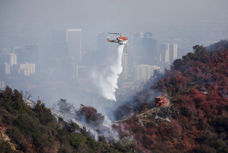 Un helic&oacute;ptero arroja agua mientras un incendio forestal arde en el &aacute;rea de Kenter Canyon en Los &Aacute;ngeles, el lunes 28 de octubre del 2019. 