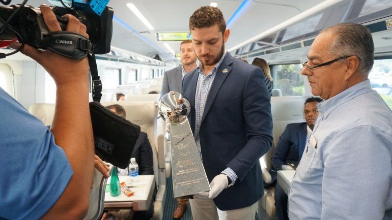 Felipe Angulo, gerente de mercadeo del Comit&eacute; Anfitri&oacute;n de Miami del Super Bowl LIV, sostiene el trofeo de la temporada perfecta ganada por los Dolphins de Miami en 1973, el lunes 9 de diciembre del 2019 en la estaci&oacute;n del tren Brightline en West Palm Beach.