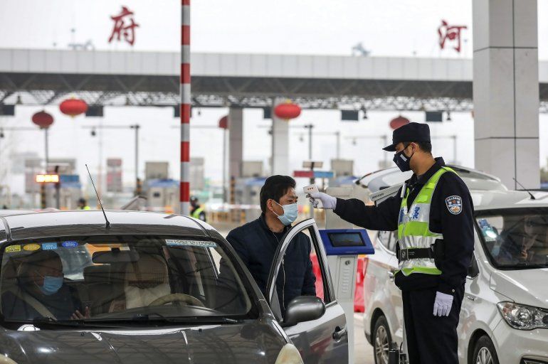   Un policía usa un termómetro digital para chequear la temperatura de un automovilista en un punto de peajes en una carretera en Wuhan, en el centro de China.