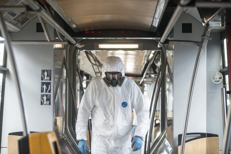 Un hombre con un traje especial camina por uno de los vagones de un tren en momentos en los que el avance del coronavirus amenaza con m&aacute;s fuerza.