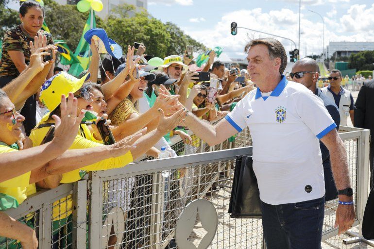    El presidente brasile&ntilde;o Jair Bolsonaro saluda a sus partidarios frente al Palacio de Planalto, despu&eacute;s de una protesta contra el Congreso Nacional y la Corte Suprema, en Brasilia, el 15 de marzo de 2020.