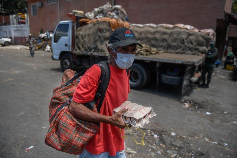 Un ciudadano en Venezuela carga huevos en su mano mientras usa mascarilla en los alrededores de un mercado municipal como medida preventiva contra el nuevo coronavirus, el 18 de marzo de 2020.