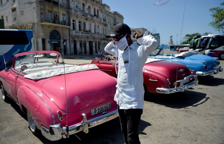 Un chofer de un auto privado al servicio del transporte del turismo se coloca una mascarilla ante el riesgo de contagio por coronavirus, en La Habana, Cuba.