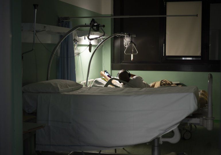 Pierre, de 54 años, utiliza una tableta para charlar con amigos y familiares, tumbado en la cama en lasección de COVID-19 en el hospital Maggiore de Parma, en el norte de Italia, el miércoles 8 de abril de 2020. 