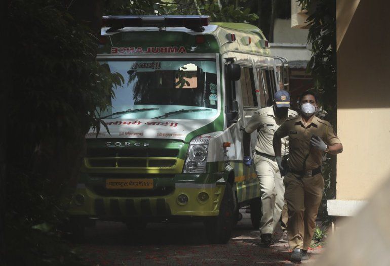 PolicÃ­as caminan cerca de una ambulancia que lleva el cuerpo del actor de Bollywood Sushant Singh Rajput antes de que salga del edificio donde vivÃ­a en Mumbai, India, el domingo 14 de junio de 2020. 