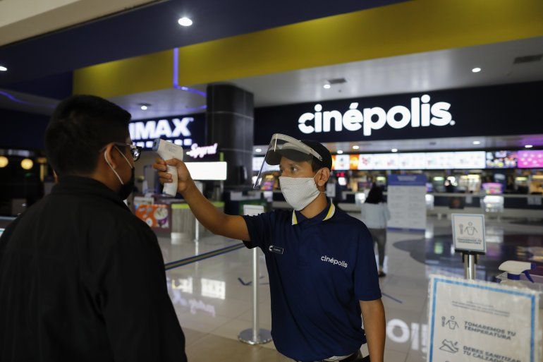 El empleado Gustavo Angel Oropeza Alvarez, de 21 a&ntilde;os, mide la temperatura de un asistente a la sucursal de cines de la cadena Cin&eacute;polis en el centro comercial Forum Buenavista de la Ciudad de M&eacute;xico.