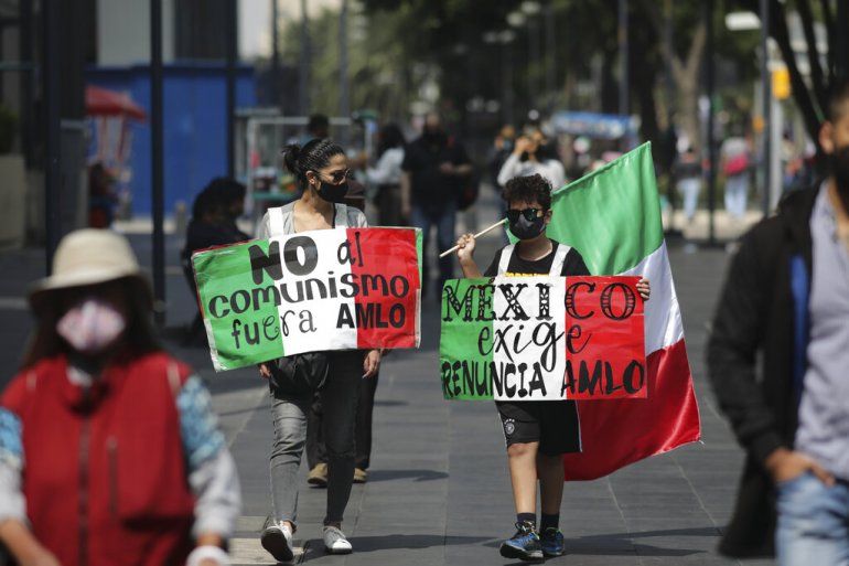 Manifestantes que exigen la renuncia del presidente mexicano Andr&eacute;s Manuel L&oacute;pez Obrador, com&uacute;nmente conocido por sus iniciales AMLO, llevan carteles en que se leen 
