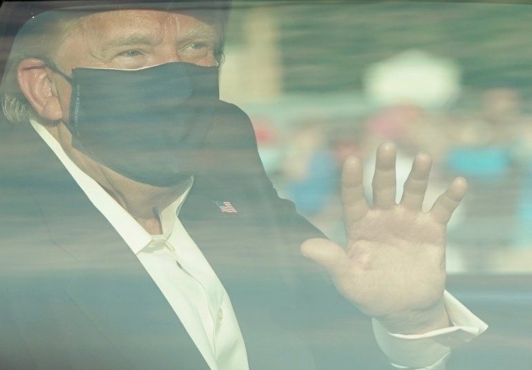 El presidente de los Estados Unidos, Donald Trump, saluda desde la parte trasera de un automóvil en una caravana fuera del Centro Médico Walter Reed en Bethesda, Maryland, el 4 de octubre de 2020.