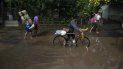 Varias personas caminan con frazadas y provisión por una calle inundada después que un cauce se desbordara. Varias personas caminan con frazadas y provisión por una calle inundada después que un cauce se desbordara.