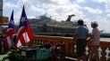 Dos turistas pasean frente a un crucero en el Puerto de San Juan, Puerto Rico. Dos turistas pasean frente a un crucero en el Puerto de San Juan, Puerto Rico.