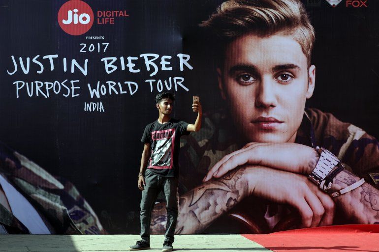  Un joven se toma un selfi frente un cartel que publicita la gira mundial del cantante canadiense Justin Bieber antes de su concierto en Bombay, India, el 10 de mayo de 2017. 