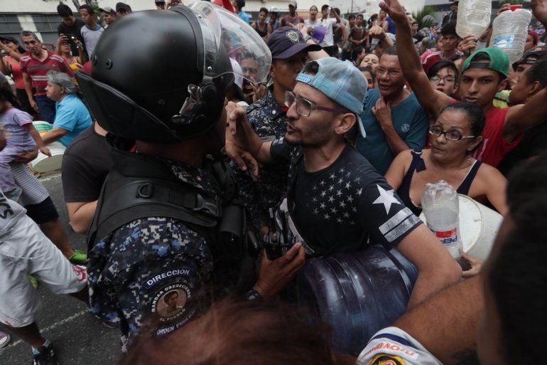 Un hombre se enfrenta a un policía durante una protesta por la falta de agua y de electricidad.