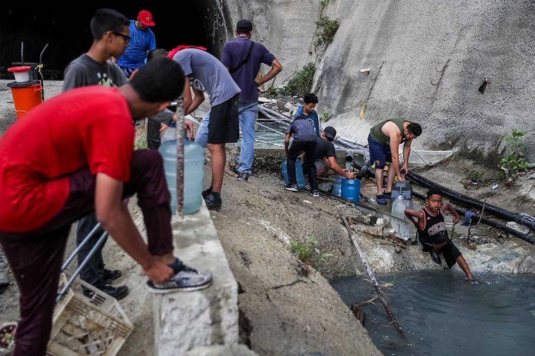 Personas afectadas por la falta de agua potable llenan sus pipotes a la orilla del río Guaire (aguas servidas). Nadie garantiza la potabilidad del agua que recogen. 