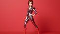 Barbie viste el traje espacial metálico de Ziggy con franjas rojas y azules, hombreras y botas de plataforma color rojo cereza. Barbie viste el traje espacial metálico de Ziggy con franjas rojas y azules, hombreras y botas de plataforma color rojo cereza.