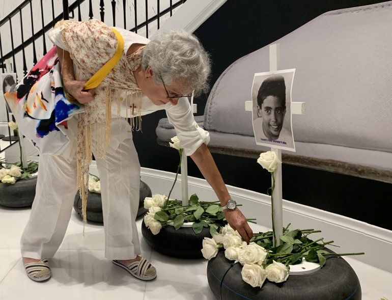 Una mujer pone una flor frente a la fotografía de uno de los niños que murieron tras el crimen del remolcador en 1994.