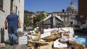 Un hombre pasa junto a una pila de basura con la cúpula de la basílica de San Pedro del Vaticano al fondo, en Roma, el 24 de junio de 2019. Un hombre pasa junto a una pila de basura con la cúpula de la basílica de San Pedro del Vaticano al fondo, en Roma, el 24 de junio de 2019.