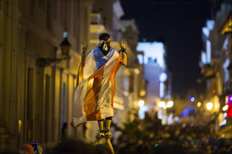 Fotografía del miércoles 17 de julio de 2019 de una manifestante envuelta con la bandera puertorriqueña en medio de las protestas que piden la renuncia del gobernador Ricardo Rosselló en San Juan, Puerto Rico.