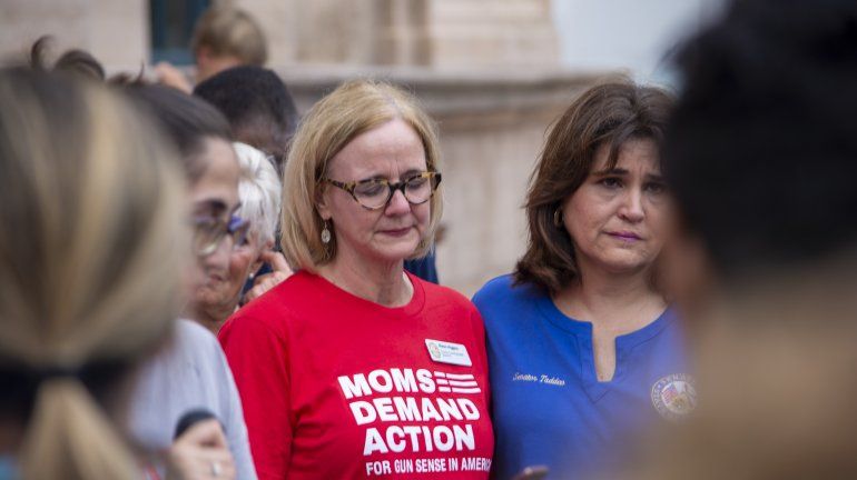 La comisionada condal Eileen Higgins (izq.) y la senadora estatal Annette Taddeo lloran mientras escuchan la lista de muertos en las matanzas de Texas y Ohio.  