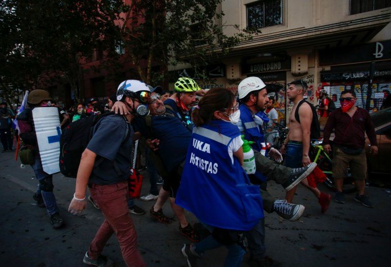 Un manifestante antigubernamental herido es llevado a un lugar seguro durante los enfrentamientos con la policía chilena en Santiago
