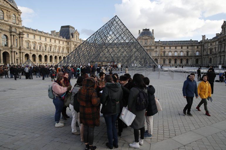 Turistas esperan y empleados en huelga se manifiestan en la entrada al Museo del Louvre