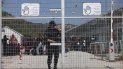 En esta fotografía del martes 5 de abril de 2016, un policía griego cierra la puerta principal de un campamento de migrantes en la isla de Lesbos, Grecia. En esta fotografía del martes 5 de abril de 2016, un policía griego cierra la puerta principal de un campamento de migrantes en la isla de Lesbos, Grecia.