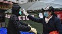 Una mujer revisa la temperatura a un ciclista que porta una mascarilla en la ciudad de Wuhan, en el centro de China, el viernes 21 de febrero de 2020. Una mujer revisa la temperatura a un ciclista que porta una mascarilla en la ciudad de Wuhan, en el centro de China, el viernes 21 de febrero de 2020.