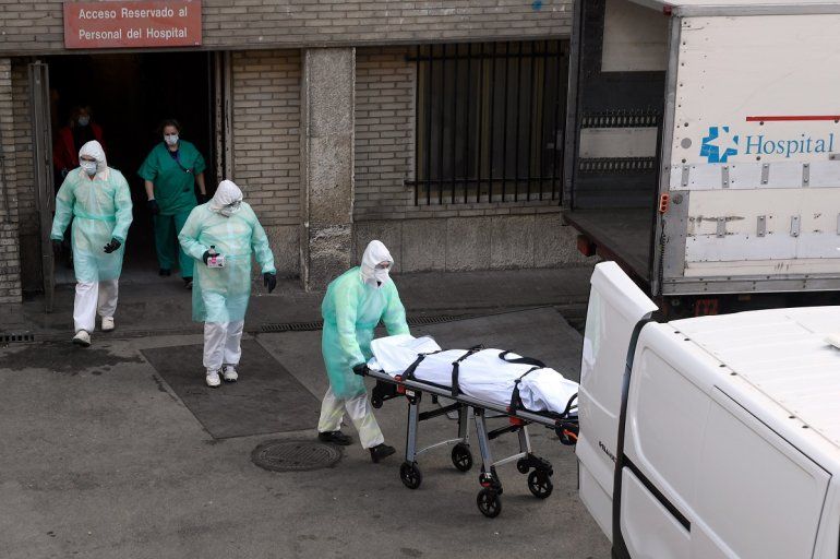 Trabajadores de salud trasladan el cadáver de uno de los fallecidos por el coronavirus COVID-19 en el hospital Gregorio Maranon