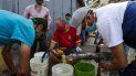Personas usan mascarillas y pañuelos como medida preventiva contra la pandemia mundial de coronavirus COVID-19 mientras recolectan agua de una tubería de la calle en Caracas, el 21 de marzo de 2020. Personas usan mascarillas y pañuelos como medida preventiva contra la pandemia mundial de coronavirus COVID-19 mientras recolectan agua de una tubería de la calle en Caracas, el 21 de marzo de 2020.