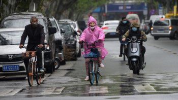 Personas con máscaras circulan en bicicletas por una calle en Wuhan, en la provincia central china de Hubei el 29 de marzo de 2020, la ciudad de origen del nuevo coronavirus. 