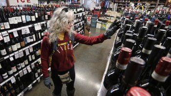 Fotografía del miércoles 25 de marzo de 2020, de Lisa MacDonald eligiendo un vino en una licorería en Seattle.