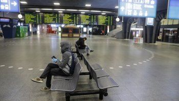 Dos personas se sientan aisladas en una estación de trenes en Bruselas. 