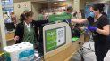 Una cajera de Publix mantiene distancia para protegerse, detrás de una plancha de plástico. Una cajera de Publix mantiene distancia para protegerse, detrás de una plancha de plástico.