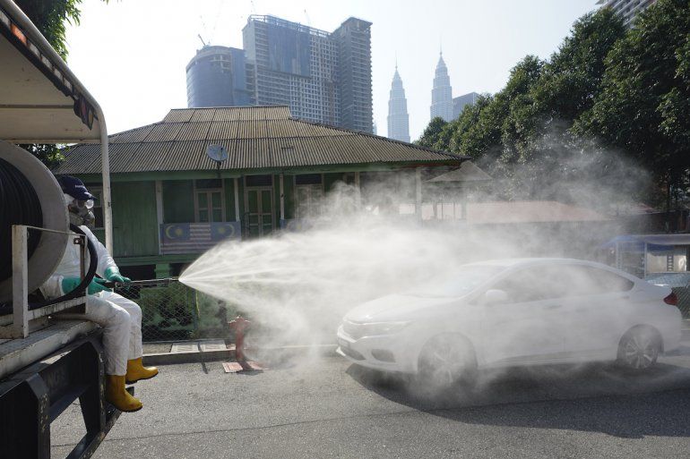 Personal sanitario rocía desinfectante sobre un barrio tradicional malasio en el centro de Kuala Lumpur