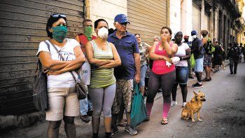 La gente hace fila para comprar alimentos, algunos usando máscarillas como precaución contra la propagación del nuevo coronavirus.