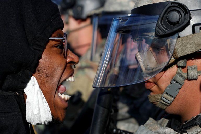   Un manifestante grita en el rostro a un efectivo de la Guardia Nacional durante una manifestación en la calle East Lake, en St. Paul, Minnesota.   