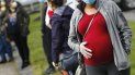 En esta fotografía de archivo del jueves 7 de mayo de 2020, una mujer embarazada que utiliza mascarilla y guantes por la pandemia de coronavirus hace fila con numerosas personas para recibir una despensa de alimentos financiada por la organización caritativa Healthy Waltham en la iglesia St. Mary en Waltham, Massachusetts. En esta fotografía de archivo del jueves 7 de mayo de 2020, una mujer embarazada que utiliza mascarilla y guantes por la pandemia de coronavirus hace fila con numerosas personas para recibir una despensa de alimentos financiada por la organización caritativa Healthy Waltham en la iglesia St. Mary en Waltham, Massachusetts.