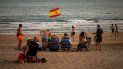 Una bandera española ondea mientras los bañistas disfrutan de un día de playa en Barbate, en la provincia de Cádiz, España, el sábado 25 de julio de 2020. Una bandera española ondea mientras los bañistas disfrutan de un día de playa en Barbate, en la provincia de Cádiz, España, el sábado 25 de julio de 2020.