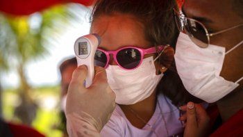 A una niña con mascarilla para protegerse del nuevo coronavirus le toman la temperatura en un puesto de control policial en la entrada de la provincia de La Habana, Cuba, el lunes 10 de agosto de 2020. 