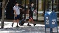 Dos jóvenes caminan por una calle de Miami, mientras se protegen del coronavirus. Dos jóvenes caminan por una calle de Miami, mientras se protegen del coronavirus.