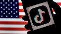 El logo de Tiktok en la pantalla de un teléfono celular y la bandera de EEUU de fondo. El logo de Tiktok en la pantalla de un teléfono celular y la bandera de EEUU de fondo.