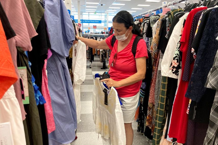 Una mujer con mascarilla selecciona prendas en una tienda de Morton Grove, Illinois.